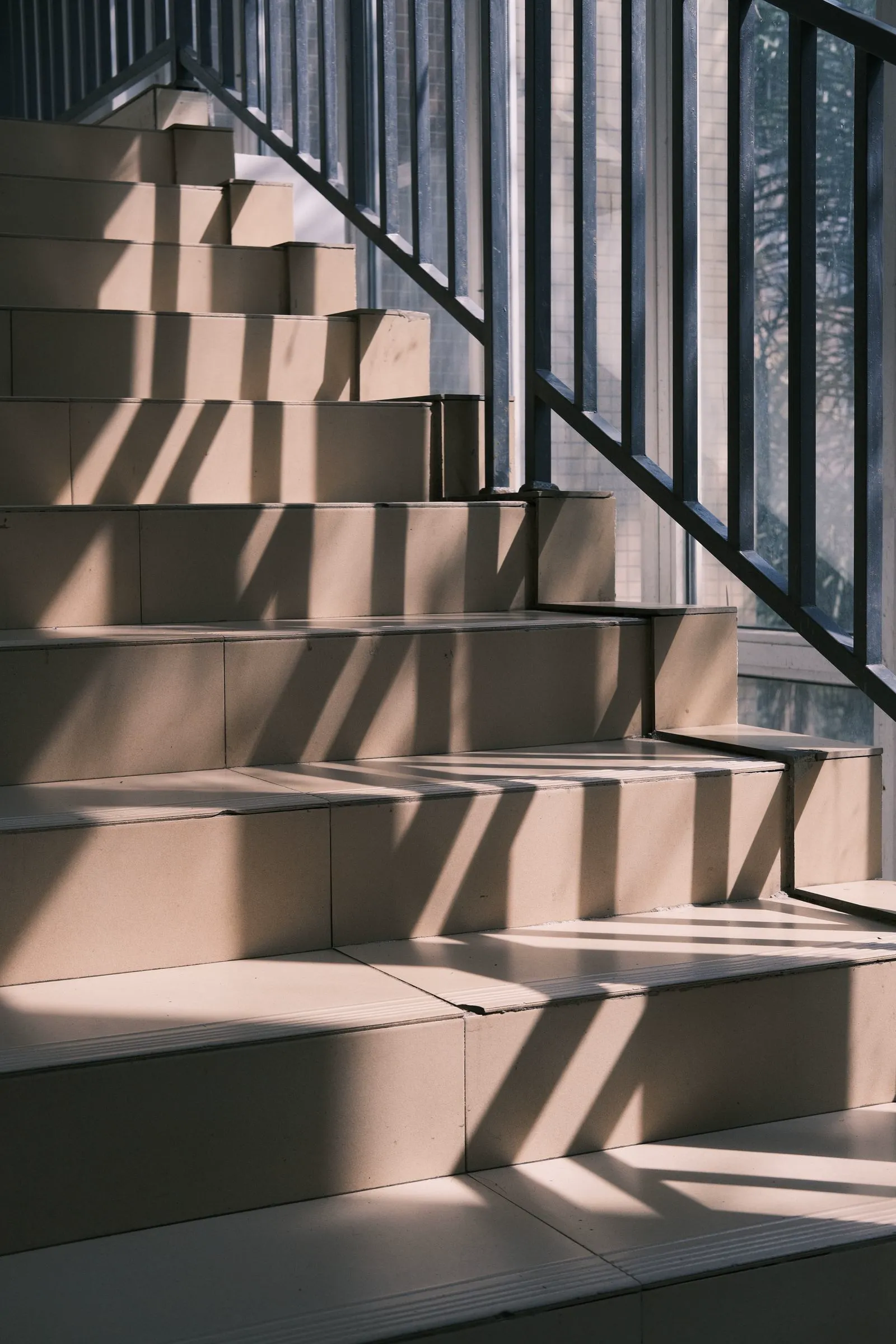 Warme Steinfliesen und dunkles Treppengeländer – Architekturaufnahme
